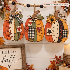 May include: A garland featuring three wooden pumpkin ornaments hanging from a jute rope with black and white beads. Each pumpkin has a patchwork design with painted hearts, stars, and plaid patterns, accented by fabric bows and wooden leaves.