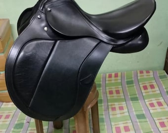 May include: Black leather English riding saddle with a brown wooden stool.