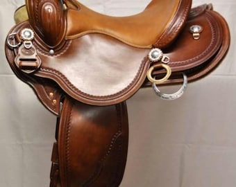 Könnte beinhalten: Ein brauner Ledersattel mit silbernen Beschlägen und einem geprägten Design. Der Sattel steht auf einem Holzständer.