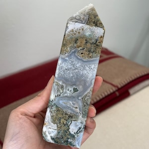 May include: A light blue and green agate crystal point with a unique pattern of swirls and lines. The crystal is polished and has a smooth surface.