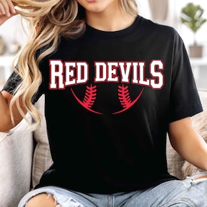 May include: Black t-shirt with the text "RED DEVILS" in white block letters with a red outline. Below the text is a red baseball design. The shirt is a casual style.