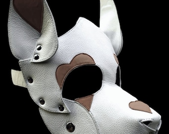 May include: White leather dog mask with brown heart-shaped accents and metal rivets. The mask has a strap for securing it to the head.