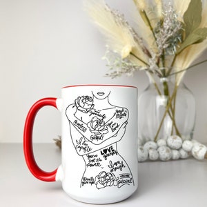 Puede incluir: Taza de cer&aacute;mica blanca con borde y asa rojos. La taza presenta un dibujo en l&iacute;nea negra de una mujer abraz&aacute;ndose a s&iacute; misma con las palabras "Love yourself" y otras afirmaciones positivas.