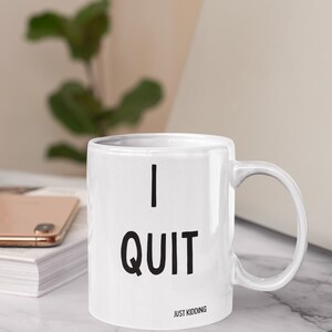 May include: White ceramic mug with black text that reads "I QUIT JUST KIDDING".