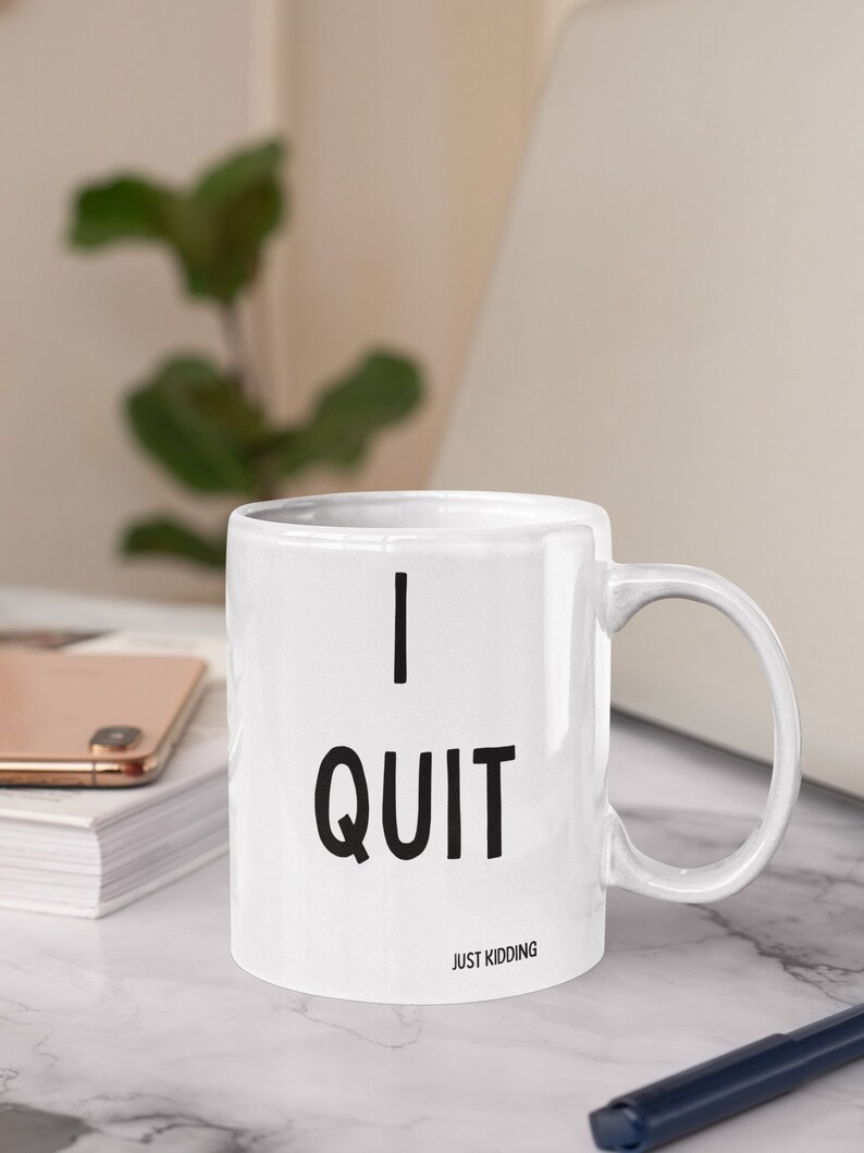 May include: White ceramic mug with black text that reads "I QUIT JUST KIDDING".