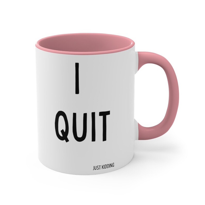 May include: White ceramic mug with a pink rim and handle. The mug has black text that reads "I QUIT JUST KIDDING".
