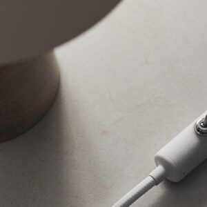 May include: A white cord with a white inline switch. The switch has a silver knob.