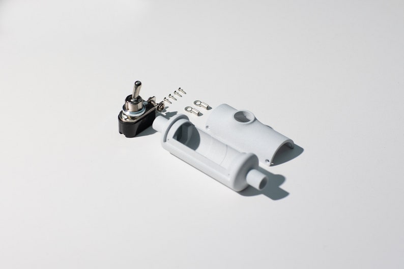 Watch inside of a light switch set on the white background.  Toggle switch, four screws, two terminals and light switch fittings. The sharp lights creates the shadow on the surface.