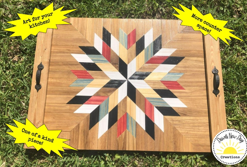 May include: A wooden serving tray with a geometric starburst design in black, white, red, and blue. The tray has two black metal handles and the text "Dawn's New Day Creations" is visible in the lower right corner.