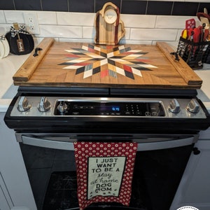 May include: A wooden serving tray with a colorful geometric design. The tray is sitting on top of a black and silver stove. The tray has a handle on each side and is made of wood. The tray is covered in a clear polyurethane finish. The tray is decorated with a colorful geometric design. The tray is sitting on top of a black and silver stove. The tray has a handle on each side and is made of wood. The tray is covered in a clear polyurethane finish.