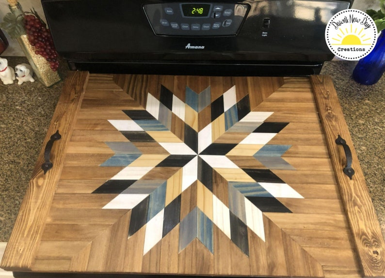 May include: A wooden serving tray with a starburst design in shades of blue, white, black, and brown. The tray has two black metal handles on the sides.