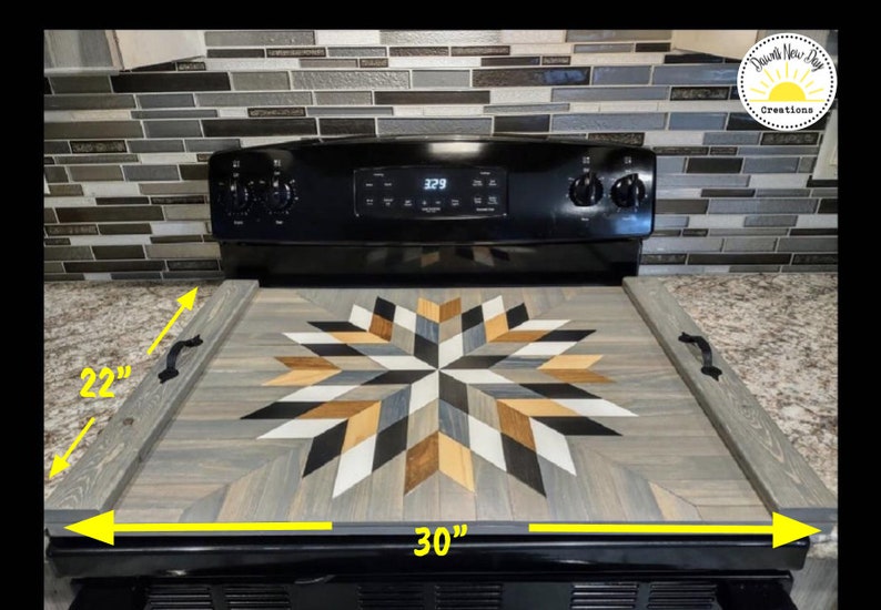 May include: A wooden stovetop cover with a geometric starburst design in shades of gray, black, white, and brown. The cover measures 30 inches by 22 inches.