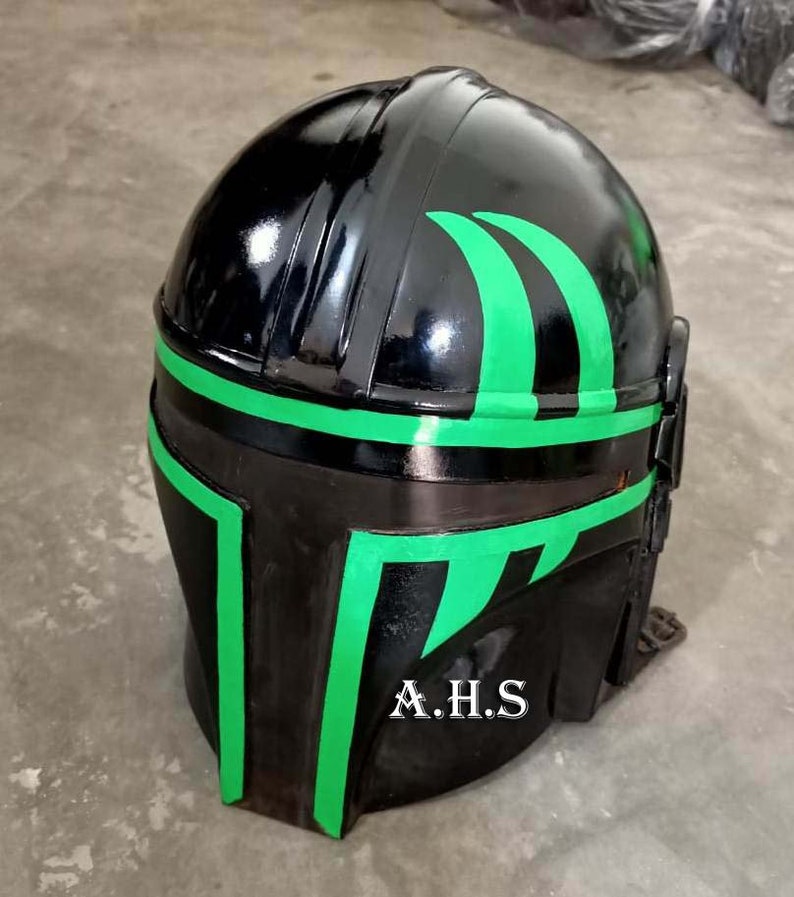 May include: A black helmet with green accents. The helmet has a glossy finish and features green stripes and angular designs. The initials "A.H.S" are printed in white on the lower front of the helmet. The helmet is likely for cosplay or costume use.