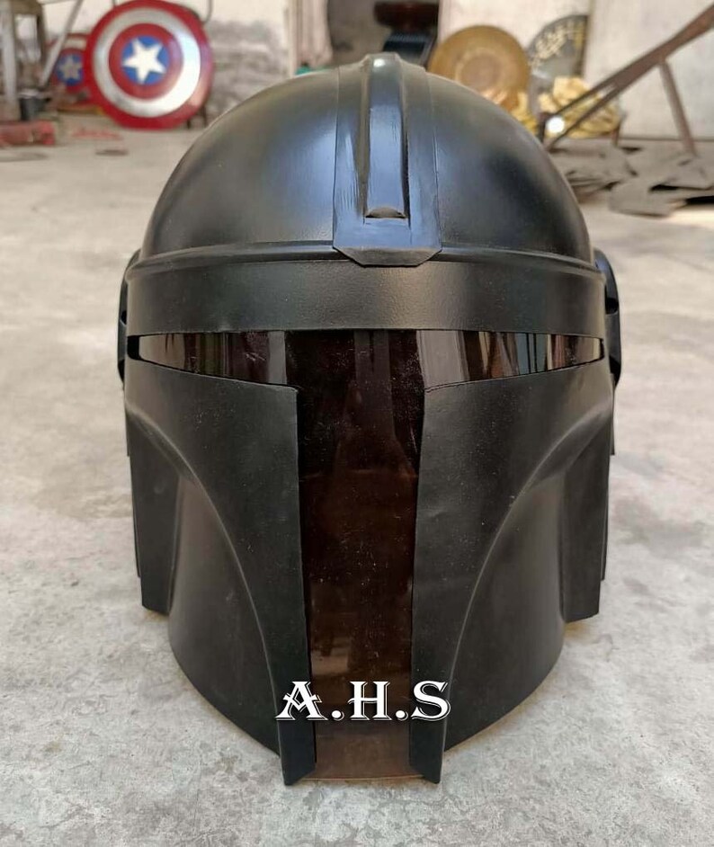 May include: A black helmet with a dark visor, featuring a sleek, angular design. The helmet has a smooth, matte finish and the text "A.H.S" is visible at the bottom. The overall aesthetic suggests a futuristic or sci-fi theme.