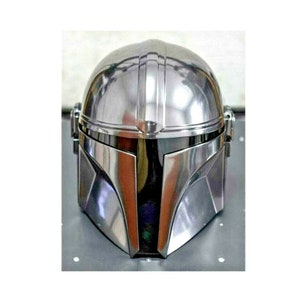 May include: A shiny, silver Mandalorian helmet. The helmet has a rounded top with vertical ridges and a distinctive visor. The metallic surface reflects light, creating highlights and shadows. The helmet is a replica from the Star Wars franchise.