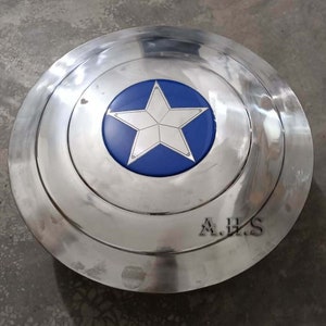 Pu&ograve; includere: Uno scudo di Captain America argentato con una stella blu al centro. Lo scudo ha un bordo rialzato e le lettere A.H.S. sono incise sul fondo.