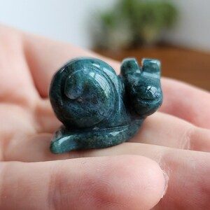 May include: A green jade snail sculpture. The snail is carved in a realistic style and has a detailed shell.