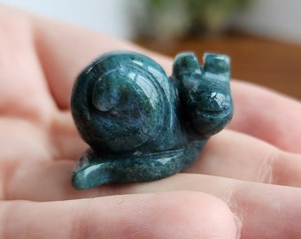 May include: A green jade snail sculpture. The snail is carved in a realistic style and has a detailed shell.