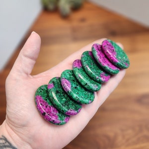 May include: A stack of eight green and pink tumbled stones. The stones are smooth and polished, with a variety of patterns and swirls.