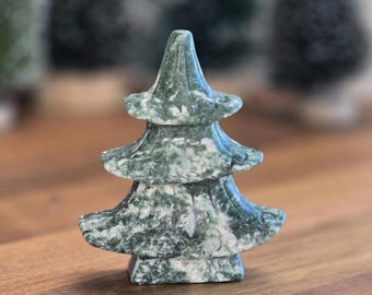 May include: A carved stone figurine shaped like a three-tiered pagoda or evergreen tree. The object features a mottled pattern of deep forest green and white mineral inclusions, with a smooth, polished surface and a wide, stable base.