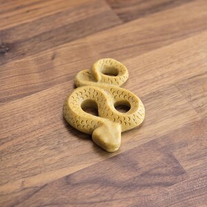 May include: A yellow snake-shaped chew toy for dogs. The toy is made of durable rubber and has a textured surface.