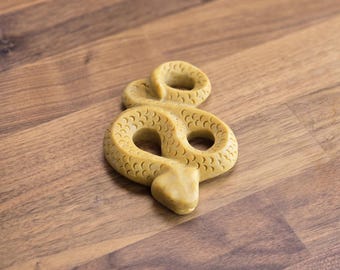 May include: A yellow snake-shaped chew toy for dogs. The toy is made of durable rubber and has a textured surface.