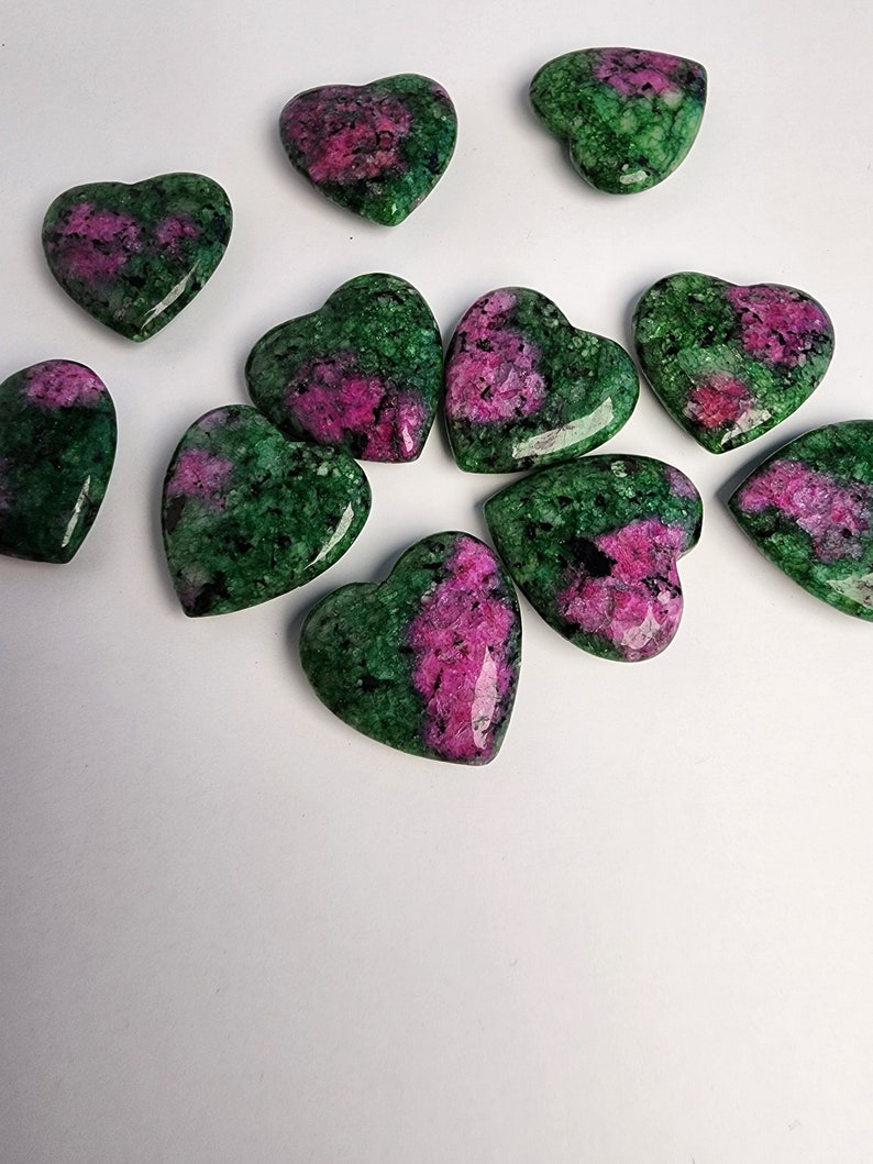 May include: A collection of 10 green and pink heart-shaped stones. The stones are polished and have a smooth surface.