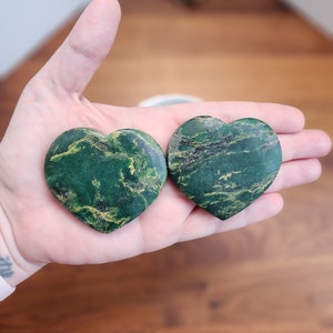 May include: Two green heart-shaped stones with gold veining. The stones are smooth and polished.