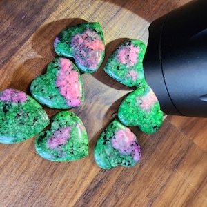 May include: Seven heart-shaped green and pink gemstones with a speckled pattern.