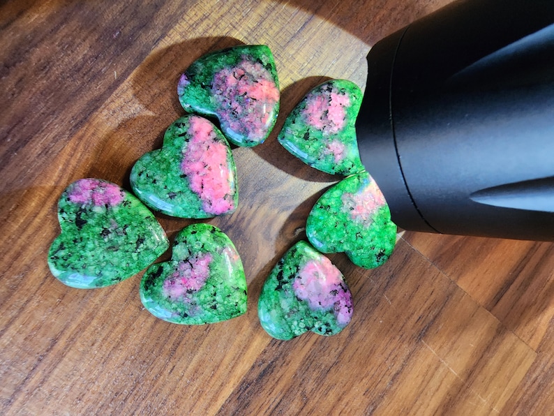 May include: Seven heart-shaped green and pink gemstones with a speckled pattern.