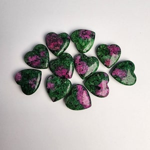 May include: A collection of ten heart-shaped green and pink gemstones. The stones are polished and have a smooth, glossy finish.