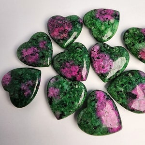 May include: A collection of ten heart-shaped green and pink gemstones. The stones are polished and have a smooth, glossy finish.
