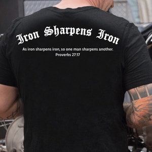 Puede incluir: Camiseta negra con texto blanco que dice "Iron Sharpens Iron" y "As iron sharpens iron, so one man sharpens another. Proverbs 27:17".