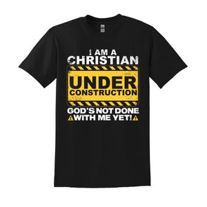 May include: Black t-shirt with a yellow and black construction sign that reads "I am a Christian Under Construction God's not done with me yet!"