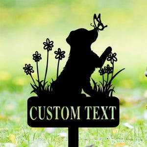 Könnte beinhalten: Schwarze Metall-Silhouette eines Hundes mit einem Schmetterling auf der Nase, umgeben von Blumen. Die Silhouette ist an einem Pfahl befestigt, an dem ein Schild mit der Aufschrift "CUSTOM TEXT" angebracht ist.