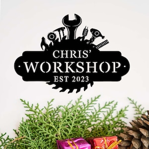 May include: Black metal sign with a saw blade design and various tools surrounding the text "CHRIS' WORKSHOP EST 2023".