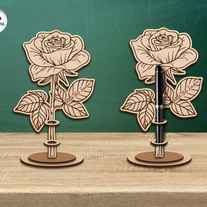 Pu&ograve; includere: Due portapenne in legno a forma di rosa con il testo "Grazie, insegnante" sulle foglie. I portapenne sono spessi 3 mm e hanno una fessura per una penna.