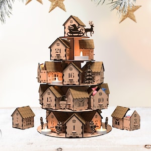 Puede incluir: Un calendario de adviento de madera con forma de pueblo escalonado. Las casas de color marrón claro están numeradas y tienen pequeñas ventanas. Papá Noel y un trineo de renos están en la parte superior. Se colocan velas de té dentro de las casas.