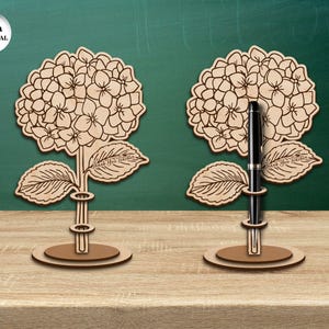 Pu&ograve; includere: Due portapenne in legno a forma di fiori di ortensia. Ogni portapenne ha uno spessore di 3 mm e presenta il testo "Grazie all'insegnante".