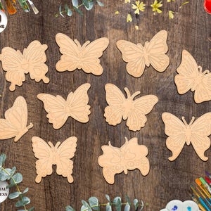 May include: Ten wooden butterfly shapes, ready to be painted. The butterflies are various sizes and have intricate wing details. The text "10 DESIGNS" is at the top of the image. The text "ANY MATERIAL THICKNESS" is at the bottom of the image.