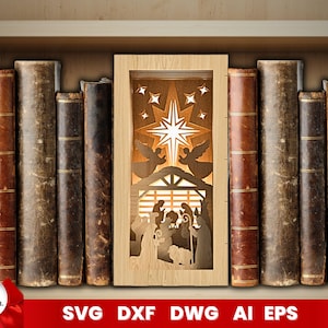 May include: A wooden cutout of a nativity scene with a star and angels above the manger. The cutout is framed and displayed on a bookshelf with a row of books on either side.