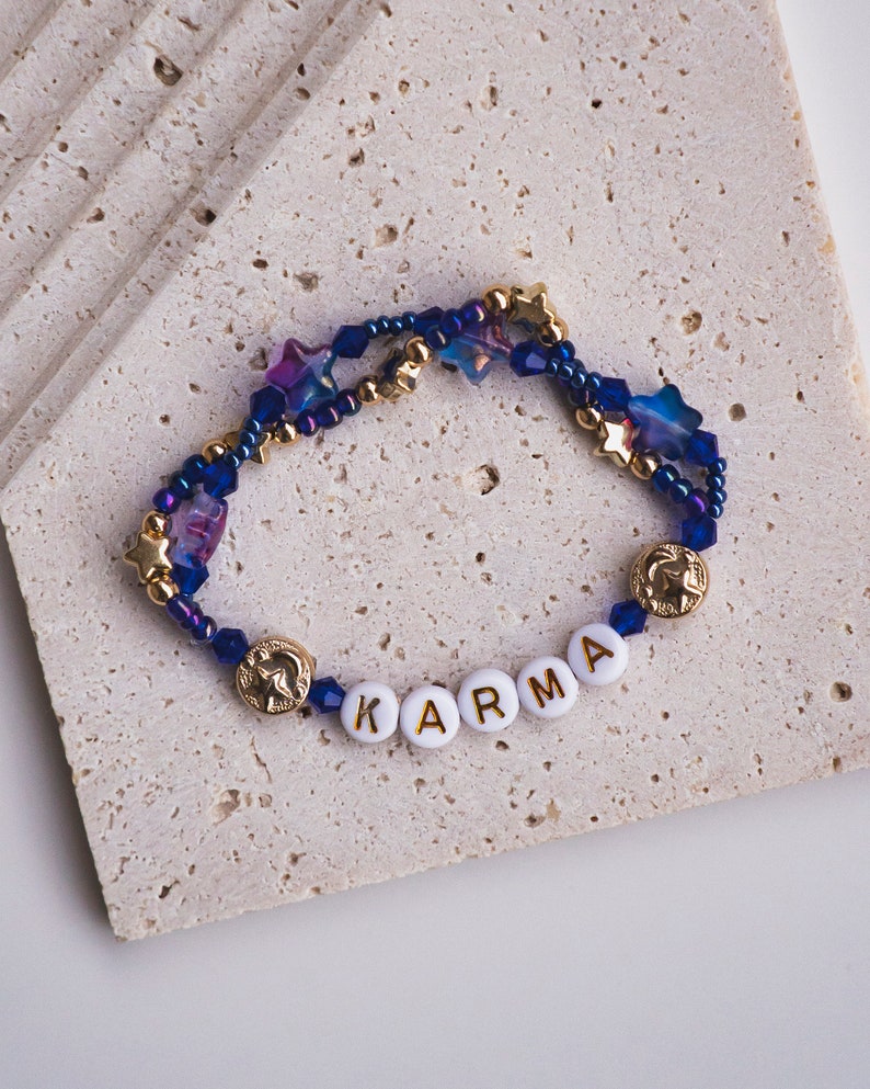 May include: A blue and gold beaded bracelet with star-shaped beads and the word "KARMA" spelled out in white beads with gold lettering.