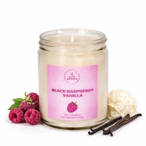 May include: A glass jar candle with a pink label that reads "Black Raspberry Vanilla." The candle is surrounded by fresh raspberries, vanilla beans, and a scoop of vanilla ice cream. The candle weighs 8 oz.