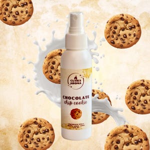 May include: White bottle of chocolate chip cookie scented room spray with a brown and white cookie image on the label. The bottle is surrounded by chocolate chip cookies and a white milk splash.