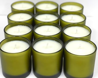 May include: A group of ten green glass candle jars with white wax and a single wick in each jar.