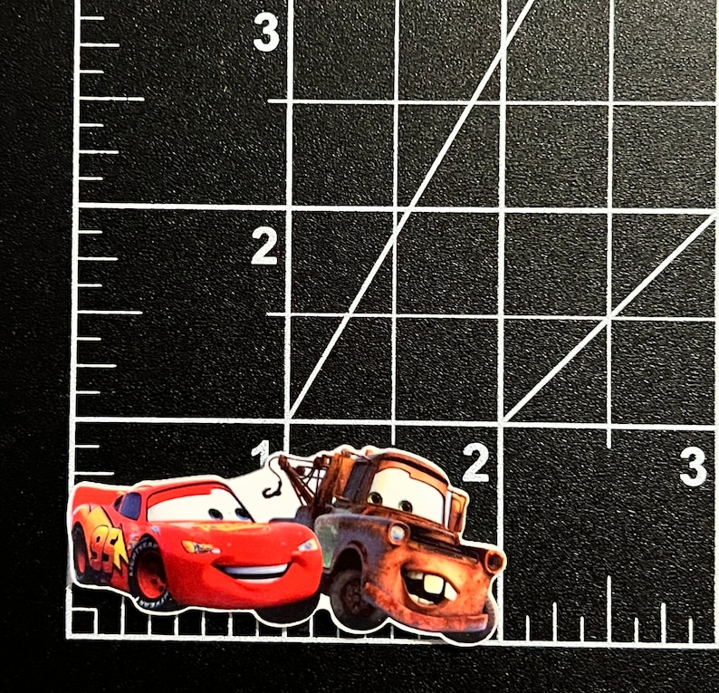 Puede incluir: Un coche de carreras rojo con el n&uacute;mero "95" blanco en el lateral est&aacute; al lado de una gr&uacute;a naranja oxidada con un gancho blanco. La gr&uacute;a tiene una cara sonriente y el coche de carreras tiene una expresi&oacute;n de sorpresa.