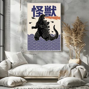 以下が含まれることがあります： 黒いゴジラのイラストと日本語のテキストが描かれた額入りのアートプリント。青い波から現れるゴジラ、オレンジ色の炎、黒い飛行機が描かれています。背景はクリーム色です。