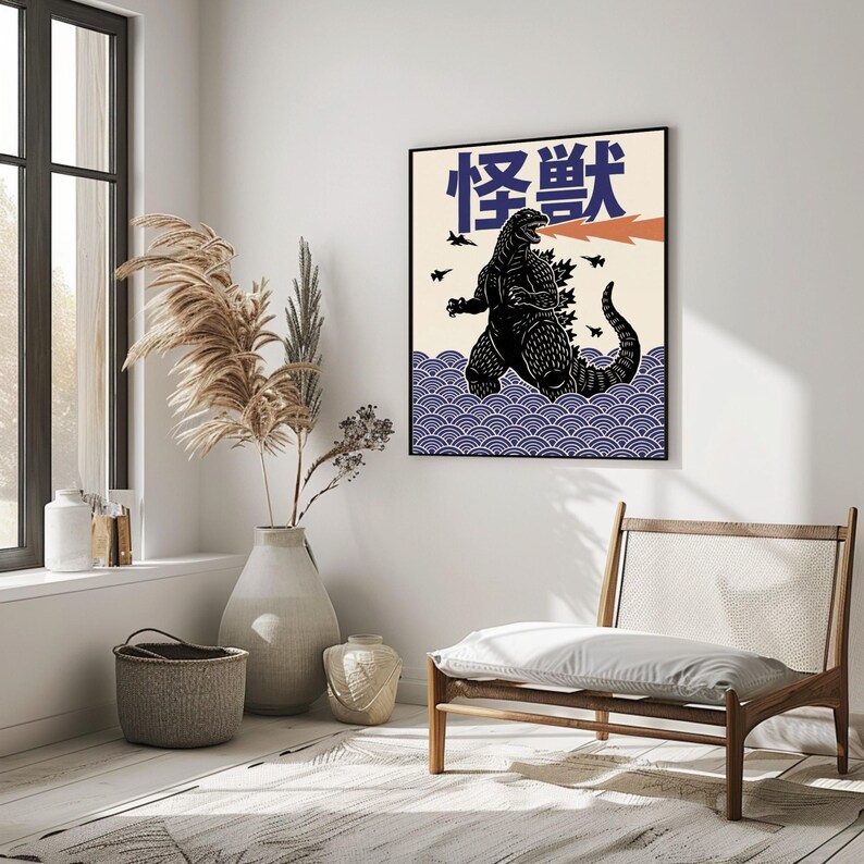 以下が含まれることがあります： 黒いフレームのアートプリント。ゴジラのイラストが描かれています。ゴジラが火を吐き、上部に日本語のテキストがあります。背景には青と白の波模様があり、黒い飛行機のシルエットがあります。
