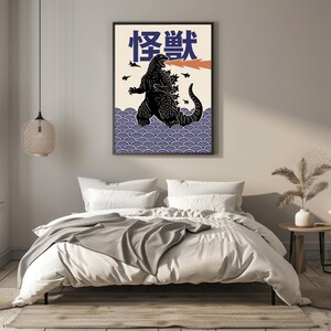 以下が含まれることがあります： 黒いゴジラのイラスト、オレンジ色の火の息、日本語のテキストが描かれた額入りのアートプリント。アートワークは、青い波模様のクリーム色の背景です。小さな黒い飛行機のシルエットが空にあります。寝室に飾られています。