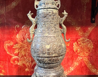 May include: A bronze incense burner with intricate carvings and a dragon design. The burner has a lid and sits on a three-legged base.